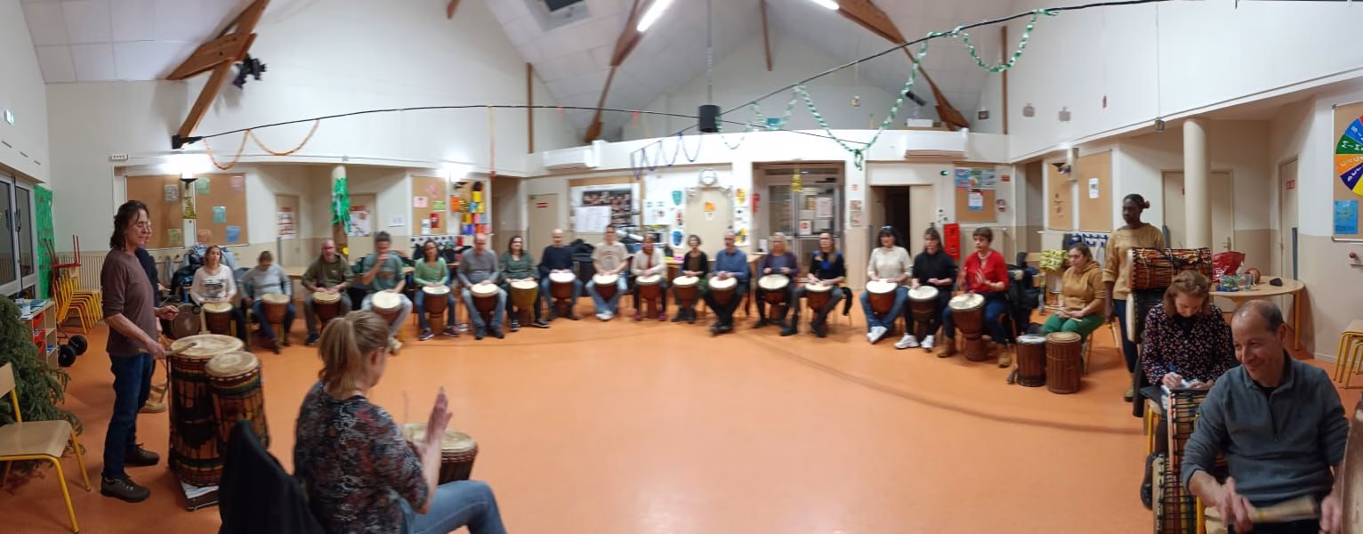 Grand cercle du cours hebdomadaire de percussion africaine de l'ACIA dans une salle