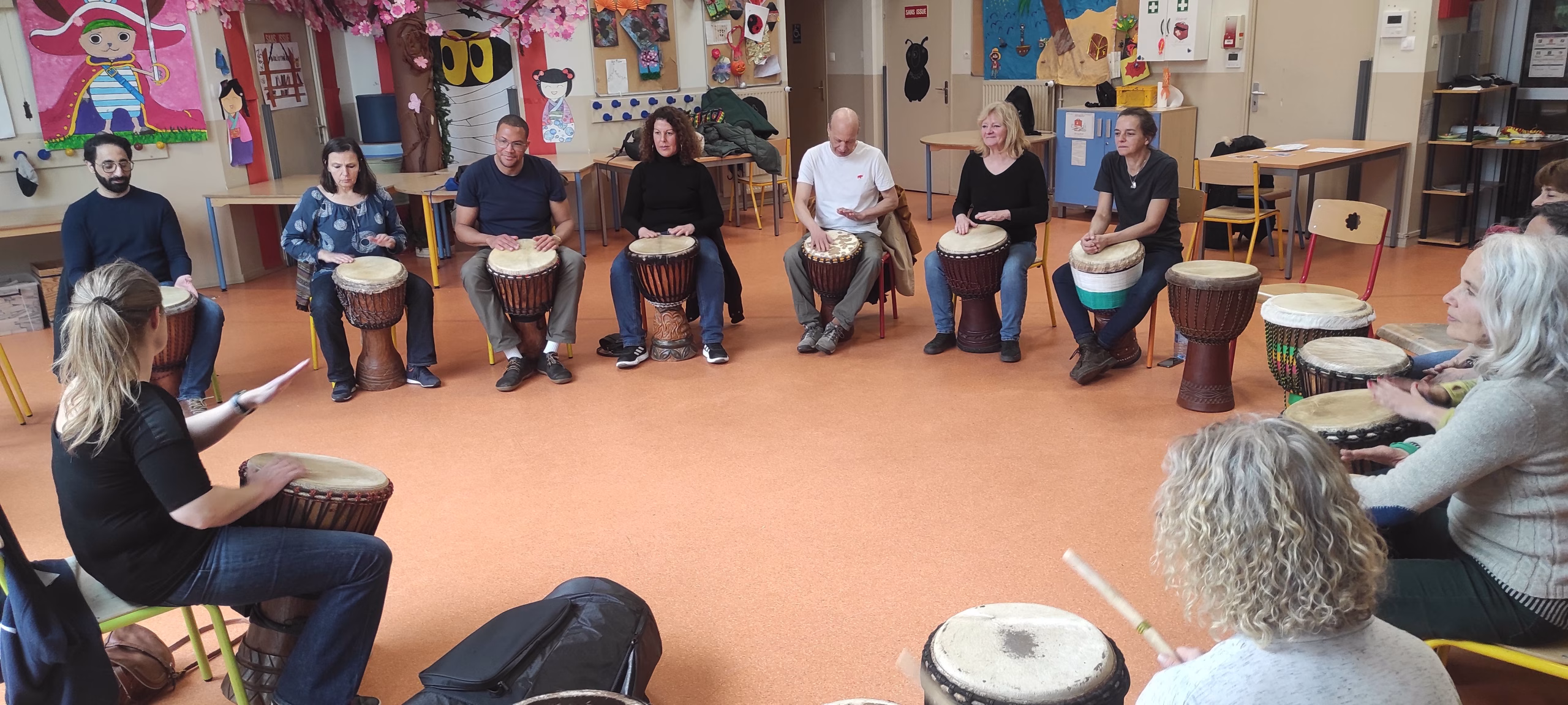 Cercle de stage de djembé de l'ACIA dans une salle, les participants assis autour de leurs instruments