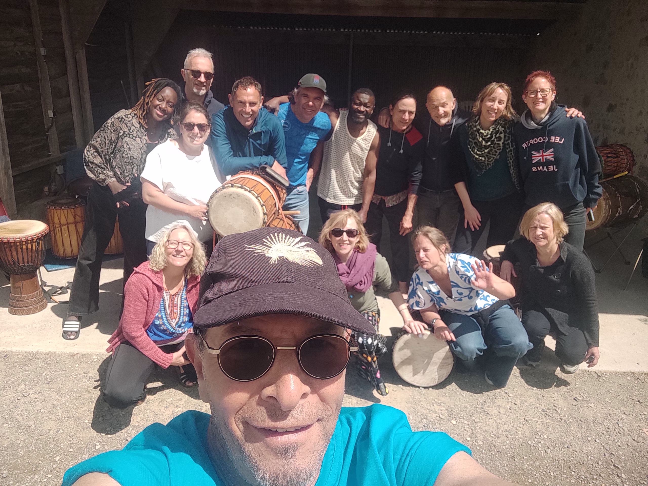 Photo de groupe des participants d'un stage de l'ACIA, réunis avec leurs djembés devant une grange
